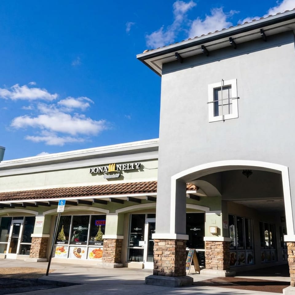 Exterior of Donnelly’s restaurant in a stucco shopping center under a bright blue sky.